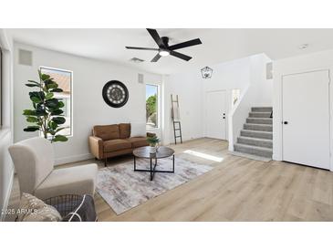 Bright living room with a stylish brown sofa, modern decor, and contemporary ceiling fan at 2112 S 160Th Dr, Goodyear, AZ 85338