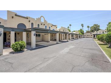 Condos feature covered parking, beige stucco, and well-maintained grounds under a clear blue sky at 2223 E Catalina Dr, Phoenix, AZ 85016
