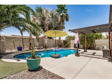 Backyard pool with desert landscaping, an umbrella, and a pergola, perfect for outdoor entertaining at 22670 N Kennedy Dr, Maricopa, AZ 85138
