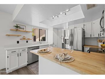 Bright kitchen featuring butcher block island, stainless steel appliances, and modern track lighting at 2455 E Broadway Rd # 122, Mesa, AZ 85204