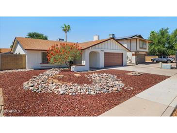 Charming single-story home featuring a well-manicured yard with unique rock landscaping and a two car garage at 3021 E Harmony Cir, Mesa, AZ 85204