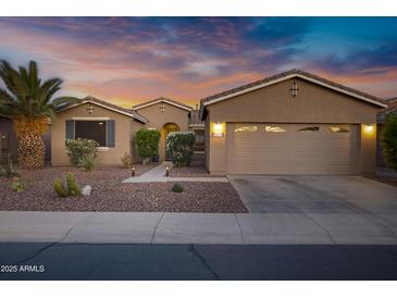 Charming single-story home featuring a two-car garage, desert landscaping, and a beautiful sunset sky at 42711 W Darter Dr, Maricopa, AZ 85138