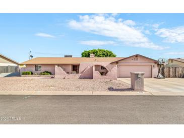 Single-story home with arched entry, desert landscaping, and driveway with basketball hoop at 6055 E Hannibal St, Mesa, AZ 85205
