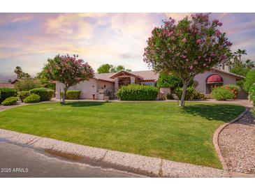 Expansive front yard featuring lush green grass and mature flowering trees at 7722 W Michigan Ave, Glendale, AZ 85308