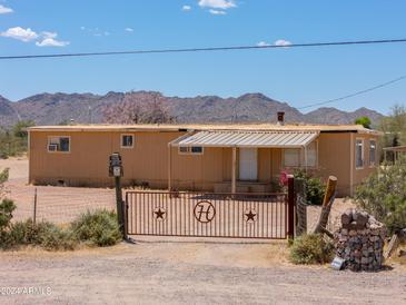 Tan single-story home with a metal gate and desert landscaping in a rural Arizona setting at 270 S Ralston Rd, Maricopa, AZ 85139