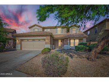 Charming two-story home featuring a two-car garage, stone accents, and a well-manicured front yard under a colorful sky at 29828 N 72Nd Ln, Peoria, AZ 85383