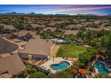 Expansive backyard featuring a sparkling pool and spa, lush landscaping, and mountain views at 6102 E Danbury Rd, Scottsdale, AZ 85254