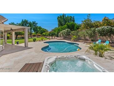 Scenic backyard with a sparkling pool, jacuzzi, covered patio, and lush landscaping at 6102 E Danbury Rd, Scottsdale, AZ 85254