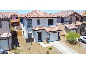 Charming two-story home featuring a tile roof, attached garage, and well-kept landscaping at 7712 S 64Th Ln, Laveen, AZ 85339