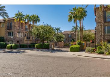Inviting stone condominium building with lush green landscaping and palm trees in a gated community at 2470 E Roma Ave, Phoenix, AZ 85016