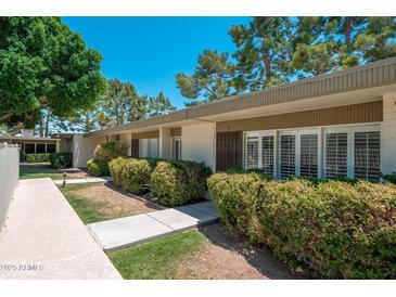 Inviting home exterior featuring lush landscaping, a well-maintained walkway, and a charming facade under a clear blue sky at 7740 E Heatherbrae Ave # 3, Scottsdale, AZ 85251