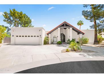 Inviting exterior with desert landscaping, arched entryway, three-car garage, and terracotta roof at 8361 E San Rafael Dr, Scottsdale, AZ 85258