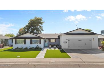 Charming single-story home with well-manicured lawn, an attached garage, and a cozy seating area by the front door at 2316 N 81St St, Scottsdale, AZ 85257