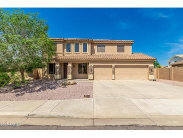 Two-story tan home features a three-car garage, desert landscaping, and a light-colored tile roof at 26272 N 73Rd Dr, Peoria, AZ 85383
