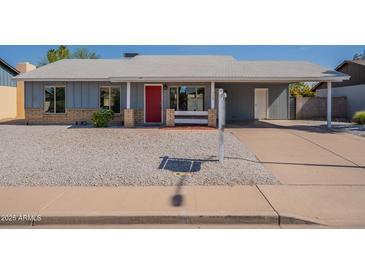 Charming single-story home featuring a bright red door, desert landscaping, and a covered carport at 719 W Pampa Ave, Mesa, AZ 85210