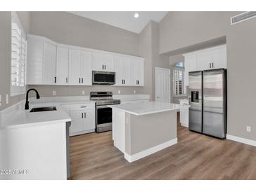 Bright kitchen features white cabinetry, stainless steel appliances, and a center island with quartz countertops at 3376 E Lafayette Ave, Gilbert, AZ 85298