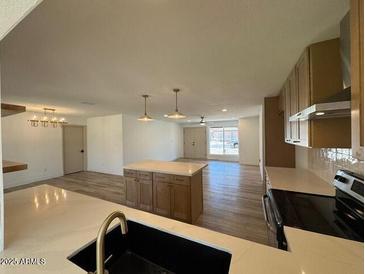 Open-concept living room with kitchen island and natural light at 3910 W Kings Ave, Phoenix, AZ 85053