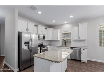 Kitchen features stainless steel appliances, granite countertops, and white cabinetry, offering a blend of style and functionality at 41041 W Somers Dr, Maricopa, AZ 85138