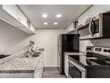 Galley kitchen featuring stainless steel appliances and speckled granite countertops at 461 W Holmes Ave # 350, Mesa, AZ 85210