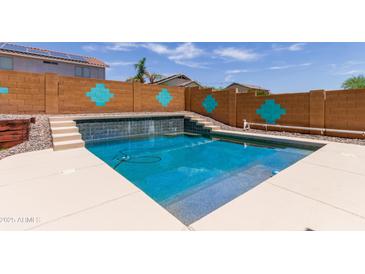 Refreshing pool with a unique tile design, surrounded by a decorative wall and steps leading to a serene waterfall feature at 25840 W Whyman St, Buckeye, AZ 85326