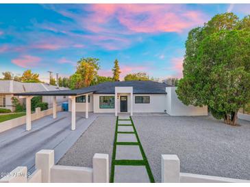 Charming home boasts modern design, desert landscaping, and a private driveway leading to a covered carport at 1535 W Berridge Ln, Phoenix, AZ 85015