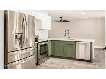 Updated kitchen with stainless steel appliances, white cabinets, and modern sink and faucet at 308 W Oraibi Dr, Phoenix, AZ 85027