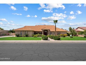 Charming single-story home with a red tile roof, manicured landscaping, and a palm tree in the front yard at 4136 E Greenway Cir, Mesa, AZ 85205