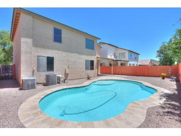 Backyard pool with a stone tile surround, mature landscaping, and a low block wall at 45113 W Buckhorn Trl, Maricopa, AZ 85139