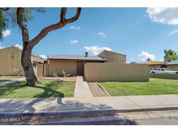 Charming single-story home with green lawn, a large shade tree, and a walkway to the front door at 921 S Hacienda Dr, Tempe, AZ 85281