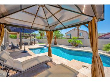 Relaxing backyard oasis with covered patio, lounge chairs, and a sparkling swimming pool for hot summer days at 18455 W San Carlos Dr, Goodyear, AZ 85338