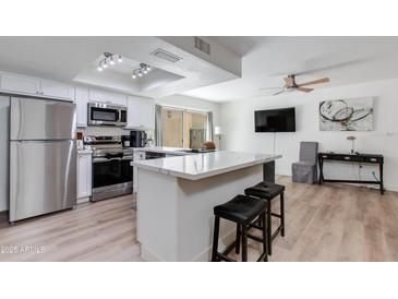 Modern kitchen features stainless appliances, white cabinets, and a large island with seating at 2021 E Osborn Rd # 9, Phoenix, AZ 85016