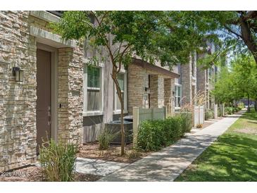 Charming townhome with stone accents, a well-maintained lawn, and a sidewalk in a desirable community at 2313 E Hidalgo Ave, Phoenix, AZ 85040