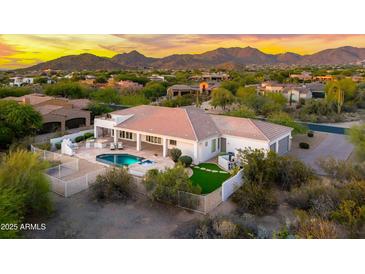 Breathtaking aerial view of a luxury home showcasing a private pool, mountain views, and desert landscaping at sunset at 3946 N Pinnacle Hills Cir, Mesa, AZ 85207