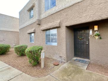 Charming home exterior showcasing a secure entry door and well-maintained landscaping at 4554 E Paradise Village Pkwy # 149, Phoenix, AZ 85032