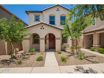 Charming two-story home with a red door, desert landscaping and an arched front entryway at 5812 W Illini St, Phoenix, AZ 85043