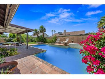 A refreshing backyard pool with lush landscaping, covered patio, and outdoor seating area at 7526 W Cheryl Dr, Peoria, AZ 85345