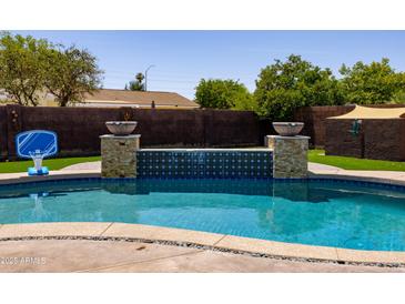 A pristine pool features a serene waterfall and a basketball hoop, offering a refreshing outdoor oasis at 1551 E Glencove St, Mesa, AZ 85203