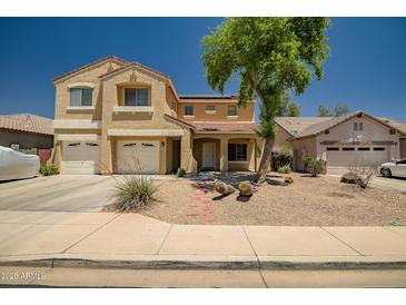 Inviting two-story home featuring a three-car garage, desert landscaping, and a red tile roof on a sunny day at 17766 W Caribbean Ln, Surprise, AZ 85388