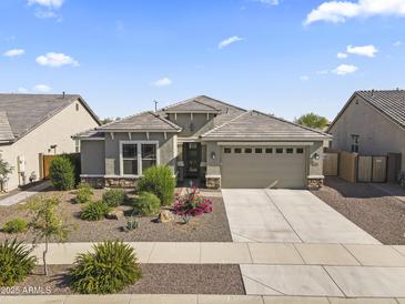 Single-story home featuring a well-manicured front yard, neutral color palette, and a two-car garage at 18865 W Mescal St, Surprise, AZ 85388