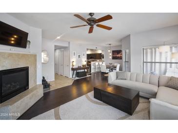 Bright living room featuring a fireplace, ceiling fan, and open layout to the kitchen and dining area at 19700 N 76Th St # 2057, Scottsdale, AZ 85255