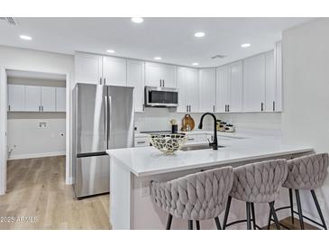 Bright kitchen features stainless steel appliances, quartz counters, and stylish bar stool seating at 4347 E Catalina Cir, Mesa, AZ 85206