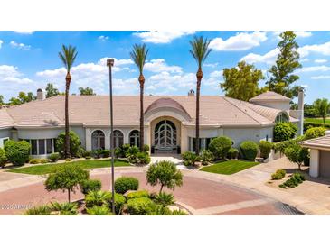 Stunning home exterior featuring lush landscaping, circular driveway, and stately palm trees at 7475 E Gainey Ranch Rd # 22, Scottsdale, AZ 85258