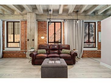 Inviting living room features exposed brick walls, concrete ceilings, wood floors, and comfortable seating at 114 W Adams St # 202, Phoenix, AZ 85003