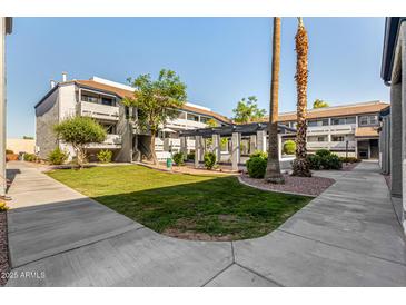 Scenic courtyard view of the apartment buildings with lush landscaping and walking paths on a clear day at 1331 W Baseline Rd # 167, Mesa, AZ 85202