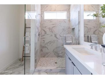 Modern bathroom with a glass-enclosed shower featuring stylish marble tile and a sleek, gray vanity with white countertop at 18047 W Long Lake Rd, Goodyear, AZ 85338