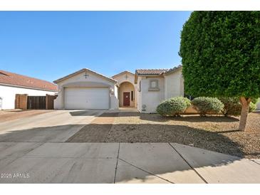 Charming single-story home with a two-car garage and a well-manicured desert landscape at 18203 W Port Royale Ln, Surprise, AZ 85388