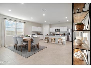 Bright eat-in kitchen with dining table, island with bar seating, and stainless steel appliances at 22650 N Lynn St, Maricopa, AZ 85138