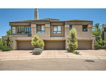 Contemporary townhome featuring three garage doors and well-maintained landscaping at 7400 E Gainey Club Dr # 206, Scottsdale, AZ 85258