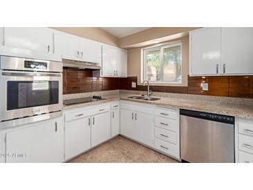 Updated kitchen features white cabinetry, stainless steel appliances, tile backsplash, and granite countertops at 10621 W Oakmont Dr, Sun City, AZ 85351