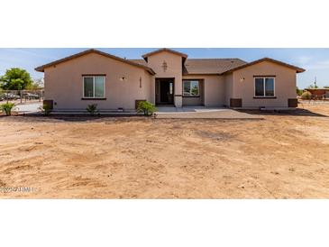 Charming single-story home with tan stucco exterior and a low-pitched roof, front yard is not yet landscaped at 20310 W Hubbard Rd, Buckeye, AZ 85326